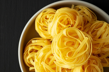 Raw Dry Tagliatelle Pasta in a Bowl, top view., a Food & Drink Photo by LiudmylaChuhunova