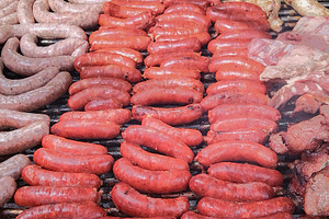 Variety of raw sausages on grill from top view, a Food & Drink Photo by DanFLCreativo