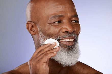 Face, skincare and antiaging with a senior black man exfoliating his skin in studio on a gray background. Beauty, treatment and cleansing with a mature male using a cotton pad for natural treatment, a Photo by Peopleimages.com