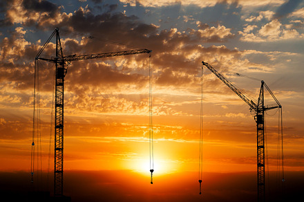 Hoisting cranes on sunset background, an Industrial Photo by PhotoVector