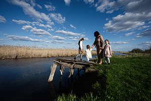 Mother and daughters walking on a rickety wooden bridge by a river in a rural l, a Person Photo by AS photostudio