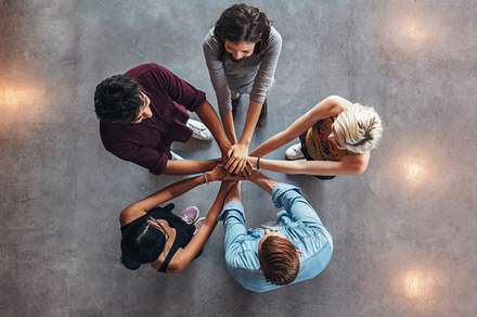 Young people making a stack containing above, college, and community, a School & Education Photo by Jacob Lund