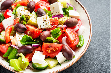 Greek salad in craft plate on black