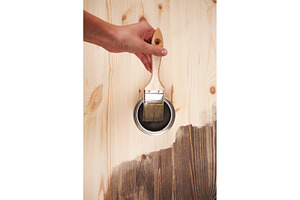 Hand with brush over can of wood