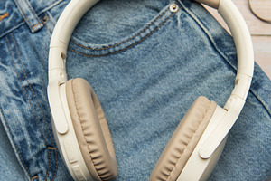 Wireless headphones lying on folded jeans and eyeglasses on wood, a Business Photo by Olena Rudo