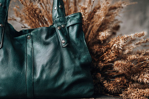 Green leather bag near dried flowers, a Photo by Beautiful things