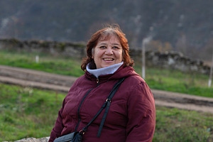 Happy older woman in a maroon jacket smiling outdoors with a nat, a Person Photo by Ales Munt