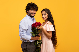 Lovers holiday. Romantic indian couple holding bouquet of flowers and looking a, a Photo by Prostock-Studio