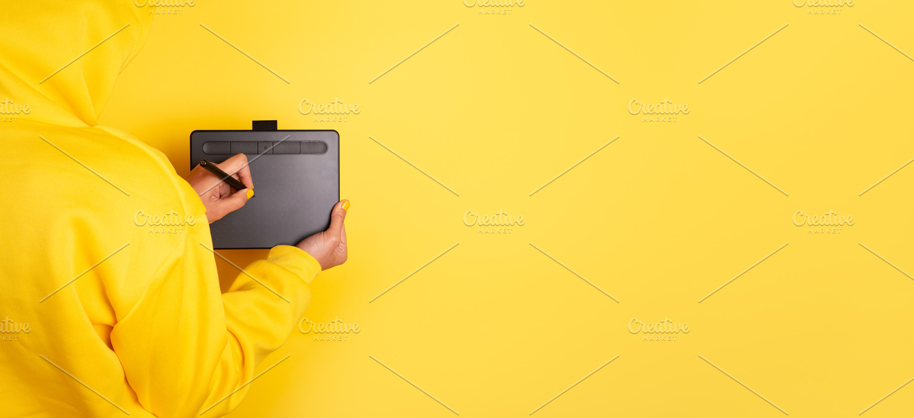 Person in yellow hoodie drawing on a graphic tablet with stylus, a Person Photo by Ales Munt