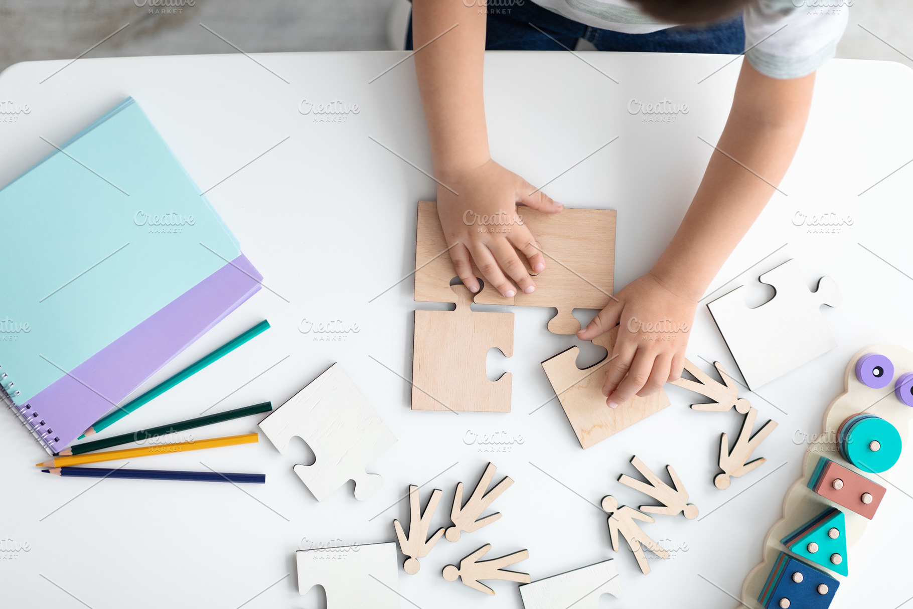 Top view hands of little child arranging wooden puzzles, symbol of public aware, a Photo by Prostock-Studio