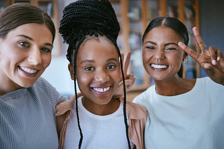 Selfie, peace sign and a group of girl friends with smile on face in classroom together. Diversity, friendship and education, happy women and university students pose for photograph in school library, a Photo by Peopleimages.com