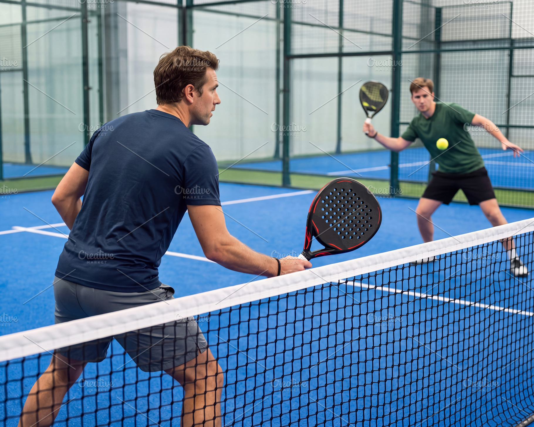 Men playing dynamic padel match on blue court with glass walls i, a Sports & Recreation Photo by Volff