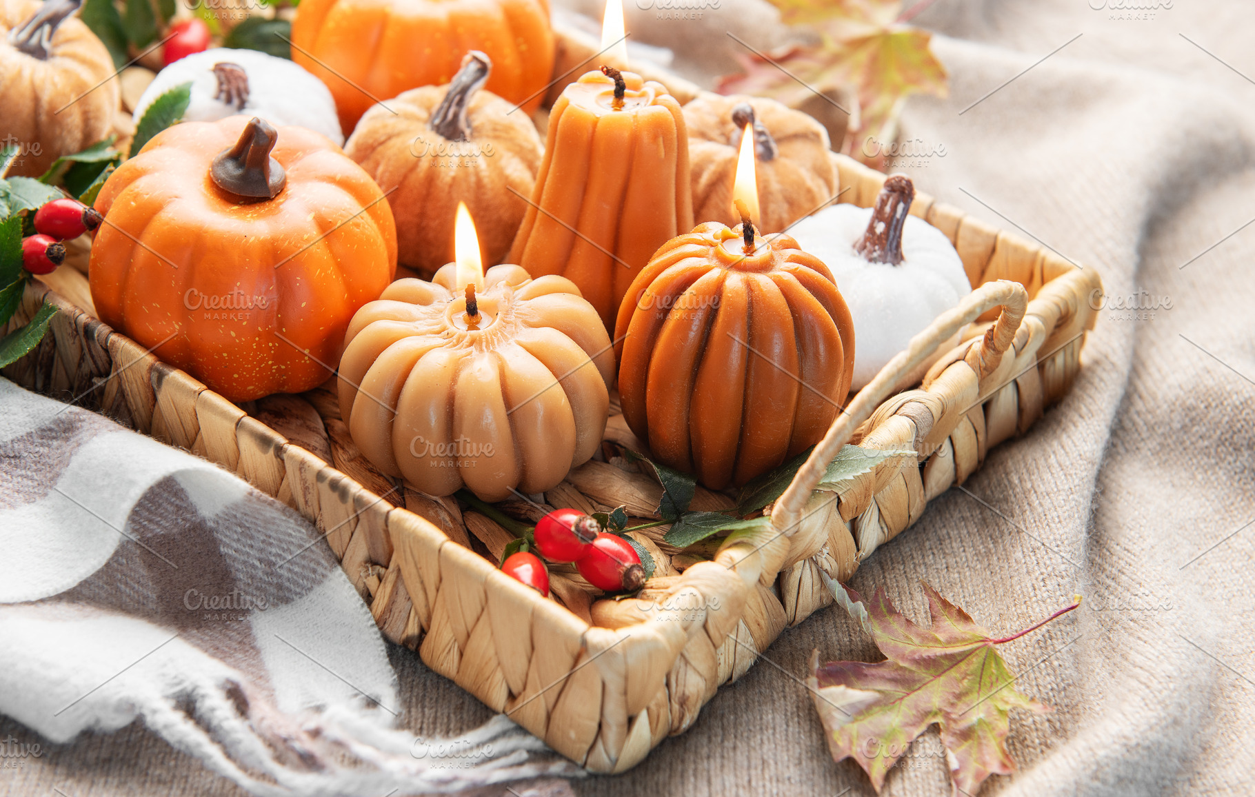 Autumn pumpkin candles burning in wicker tray on blanket, a Holiday Photo by Olena Rudo