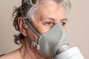 Elderly woman wearing gray gas mask indoors, a Person Photo by GoodGoods