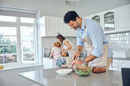 Mom, dad and child cooking in kitchen together to prepare food for lunch supper and dinner. Family, helping hands and father cutting, slice and chop with mother and girl helping clean vegetables, a Photo by Peopleimages.com