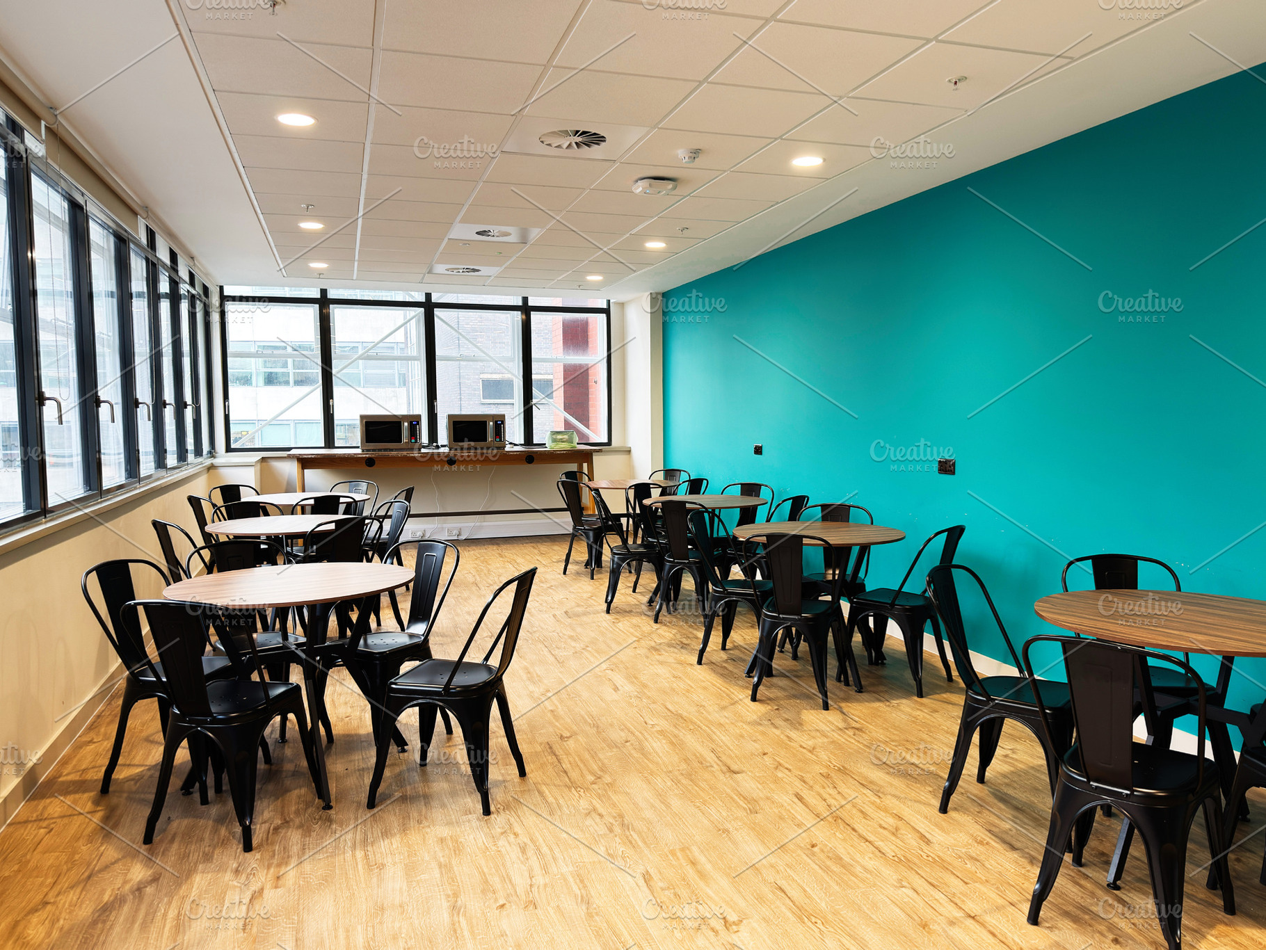 Bright breakroom in Manchester UK featuring teal wall, round tables, and black, a Photo by AS photostudio