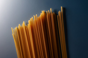 Raw spaghetti pasta strands on a dark background, preparing unco, a Photo by Studio ANNA
