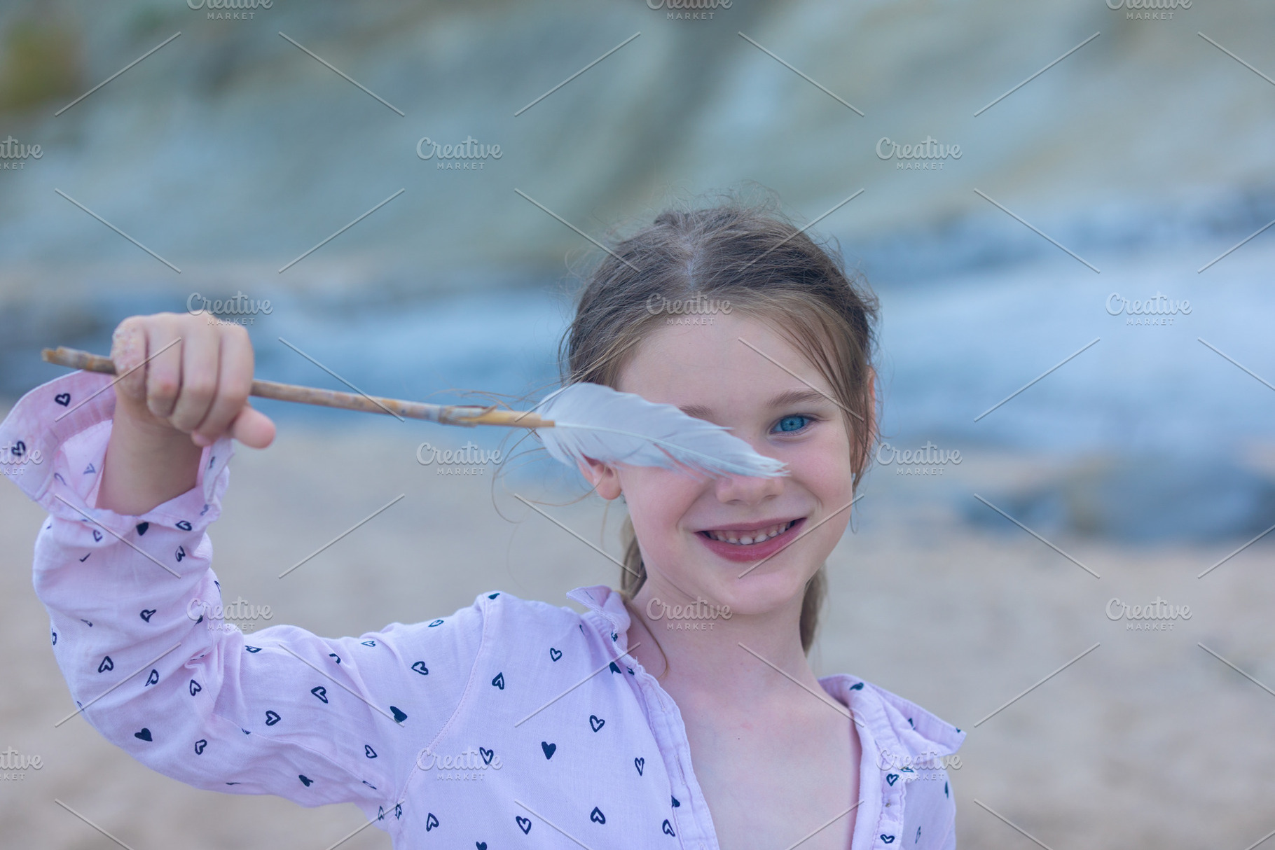Smiling girl holding a feather on a sandy beach with soft natural light and a b, a Person Photo by Ales Munt