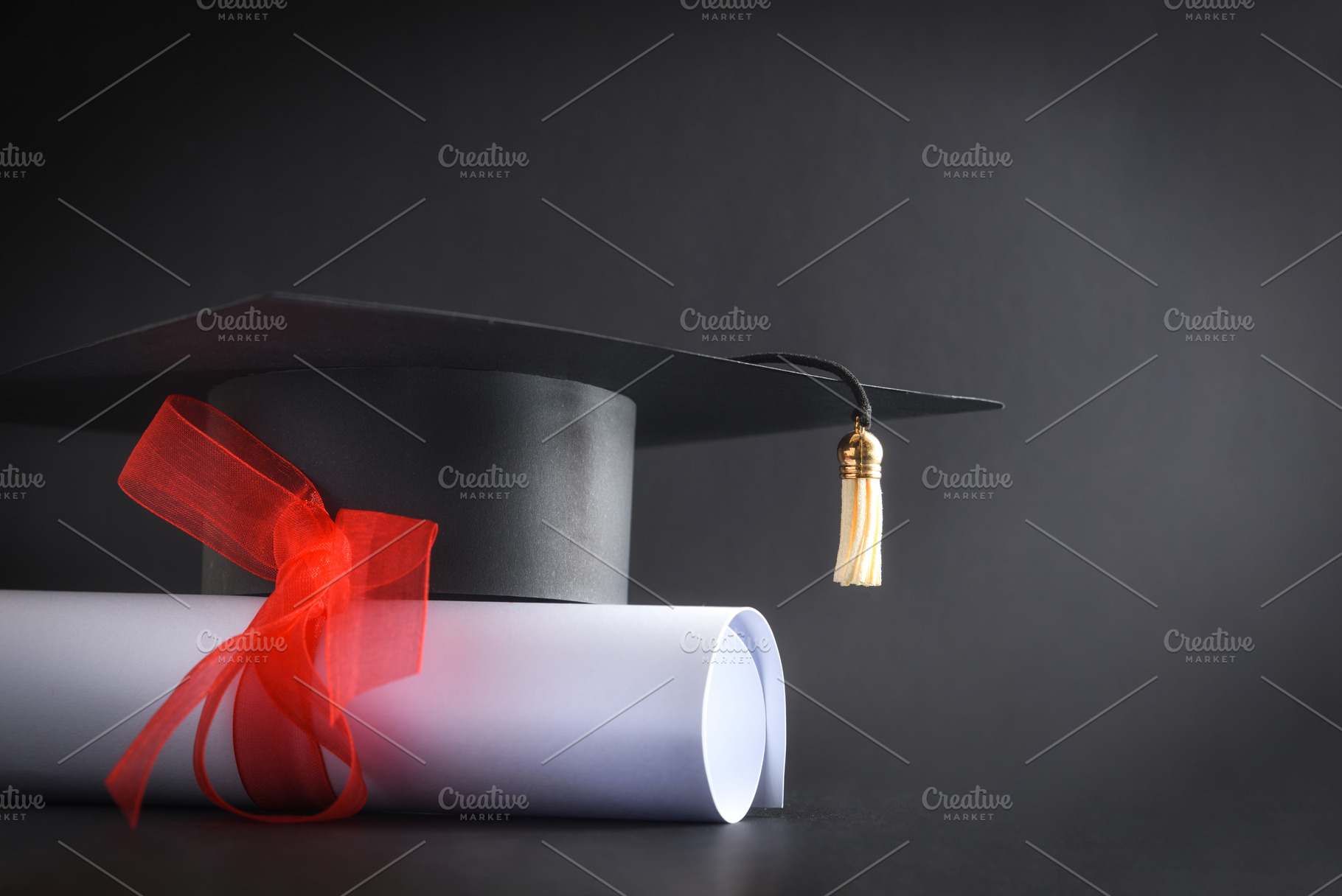 Academic cap and diploma with red ribbon isolated on black, a School & Education Photo by Davizro's Market
