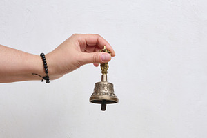A person holding a traditional Tibetan bronze bell in their hand, a Person Photo by ndanko