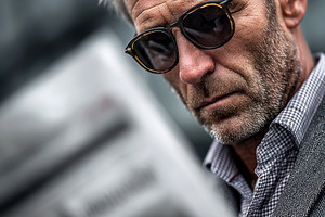 Stylish mature man with sunglasses reading a newspaper outdoors, a Photo by José Manuel Gelpi