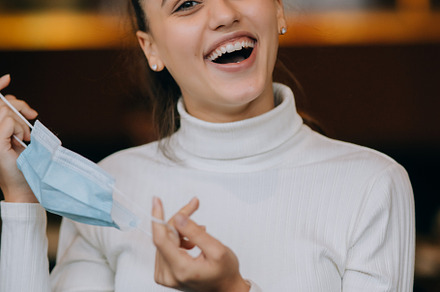 Girl in takes off her protective medical face mask