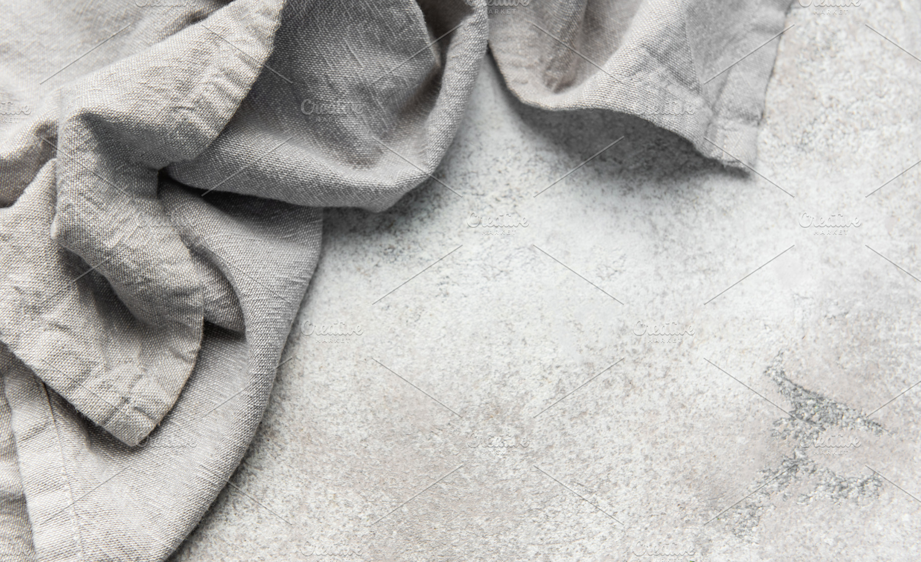 Wrinkled grey linen fabric resting on stone background, a Food & Drink Photo by Olena Rudo