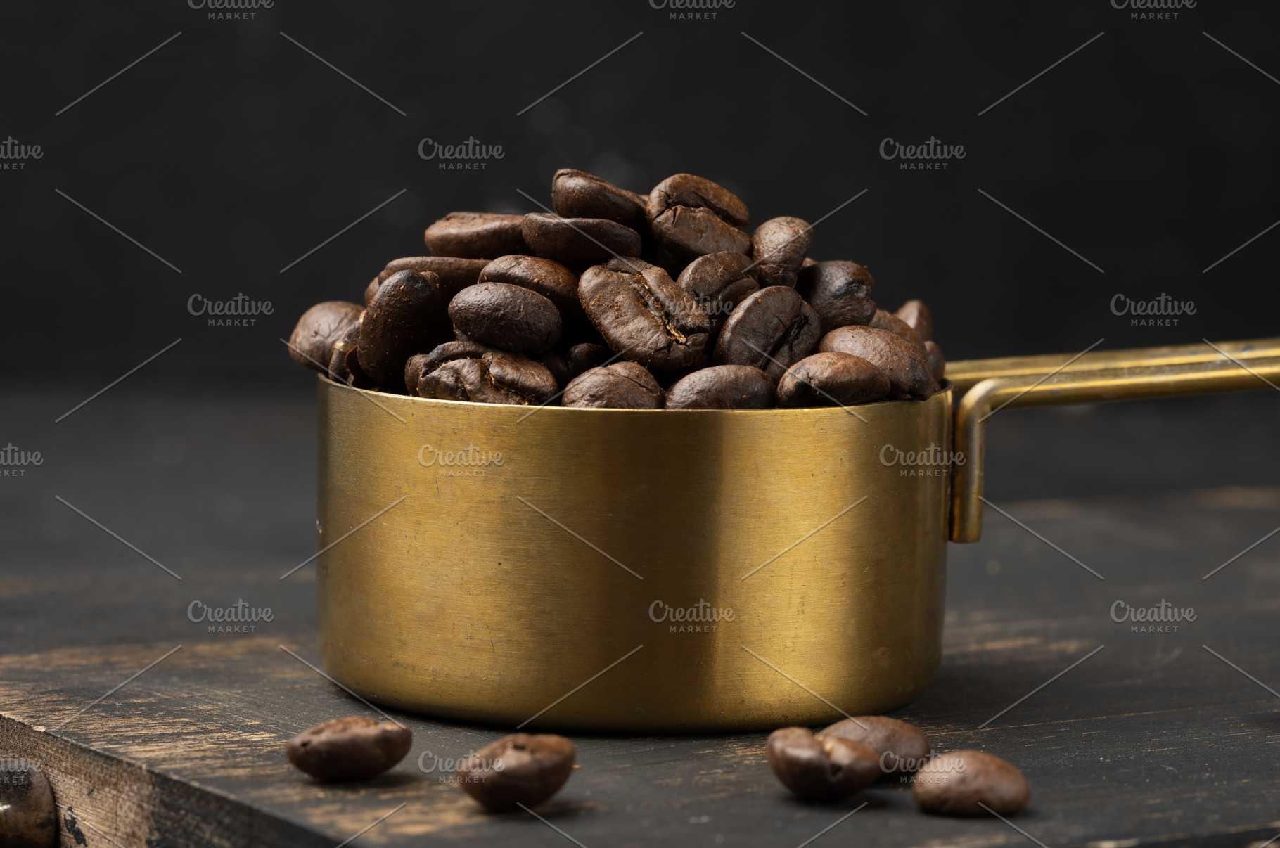 Roasted coffee beans are heaped into a golden metal measuring cu, a Food & Drink Photo by ndanko