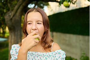 Girl eating a pear while standing in