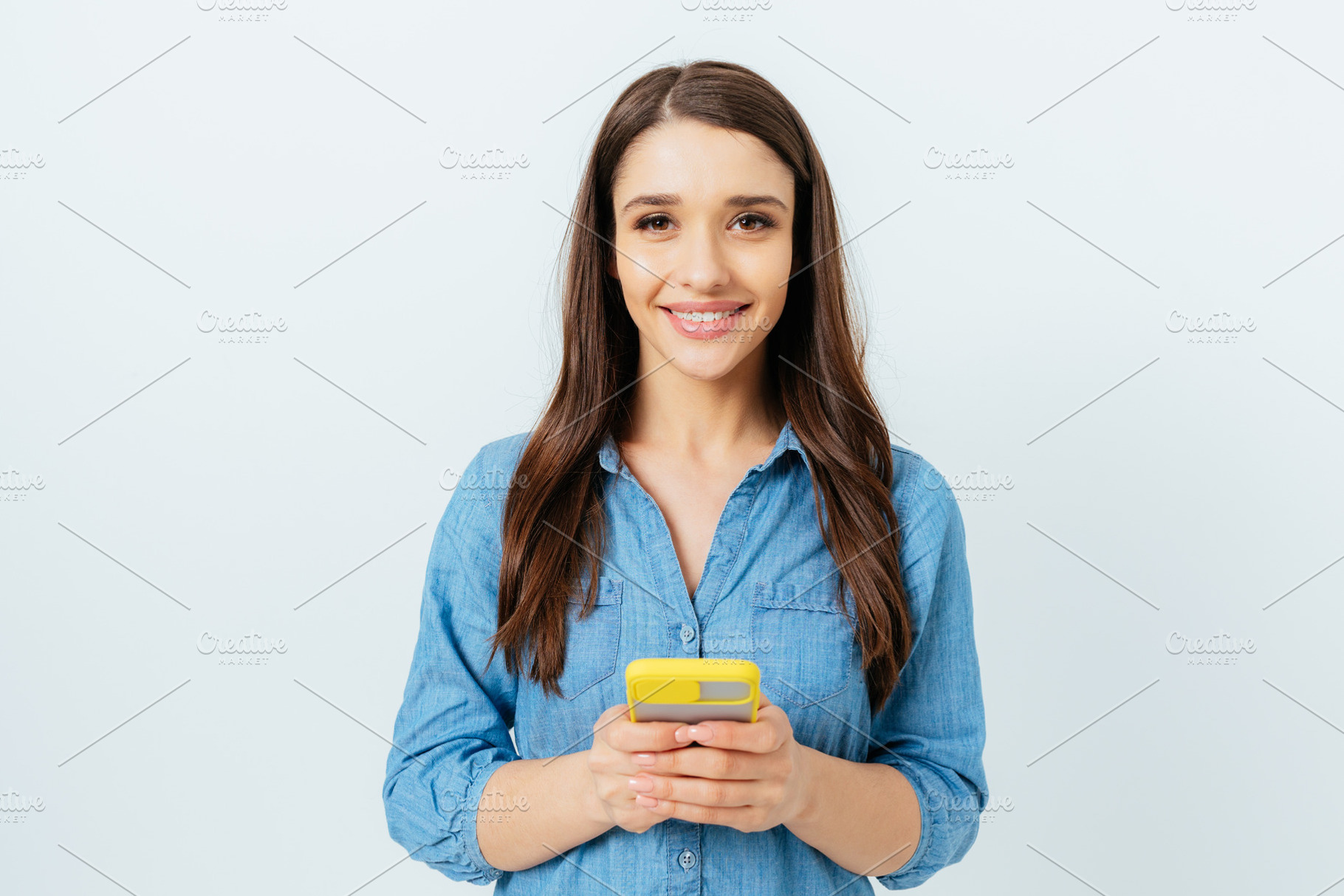 Happy young brunette woman wearing jeans shirt holding mobile ph, a Person Photo by progressman