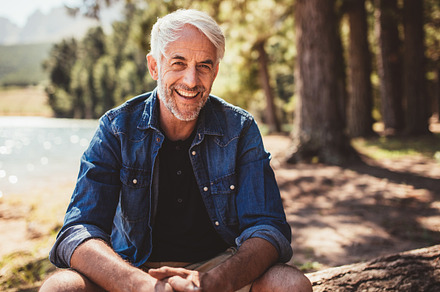 Happy mature man sitting near lake, a Person Photo by Jacob Lund