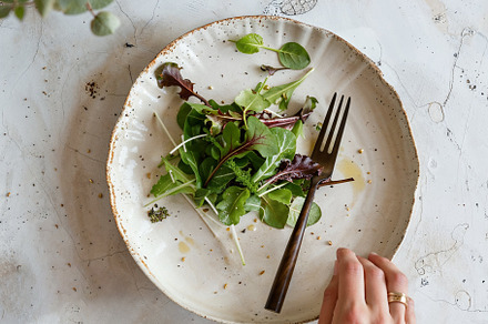 Woman hand taking salad from plate