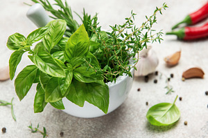 Fresh green herbs and spices in mortar with pestle for seasoning, a Food & Drink Photo by Olena Rudo