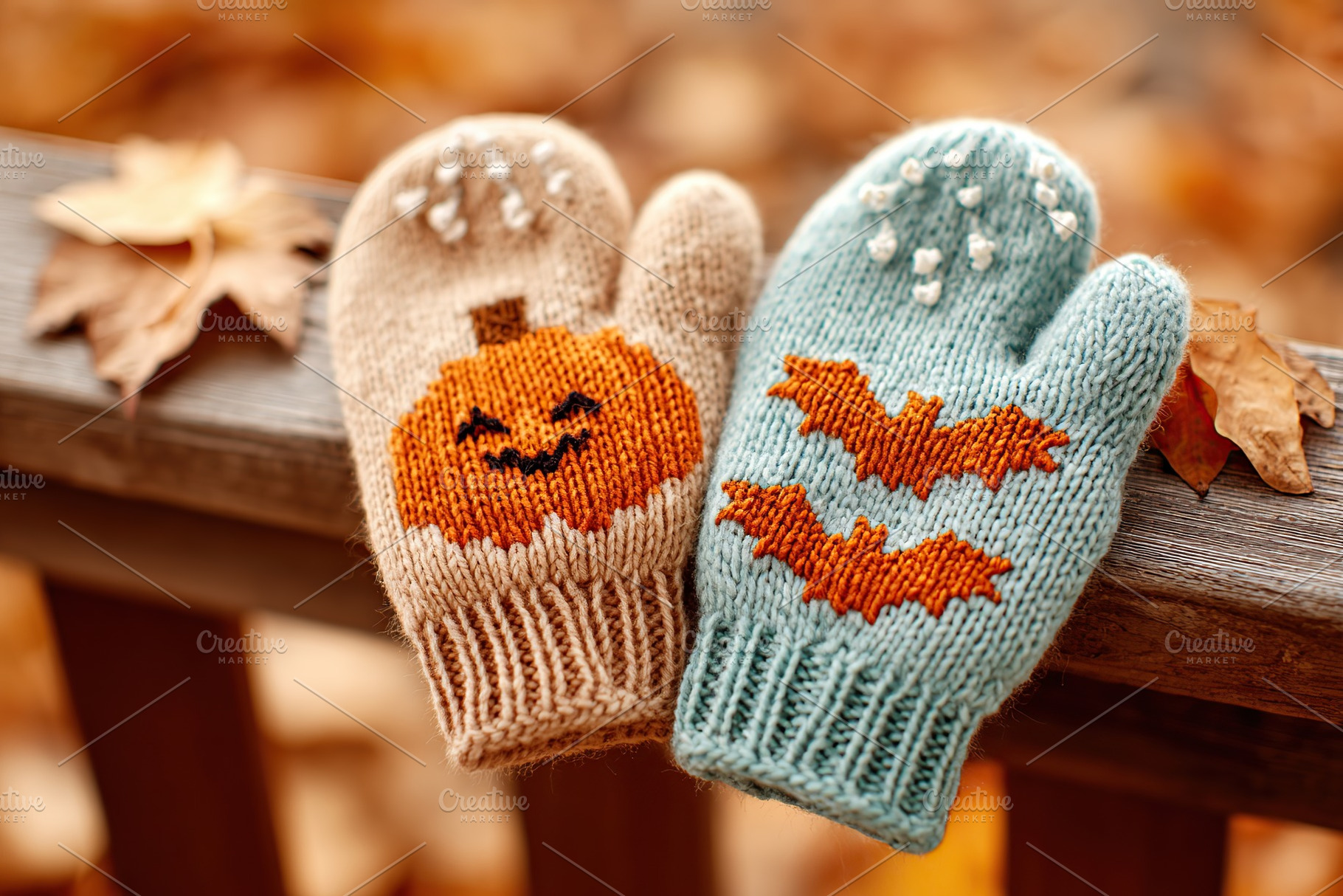 Cozy knitted mittens with Halloween designs on a wooden railing surrounded by a, a Beauty & Fashion Photo by AlyaAnd