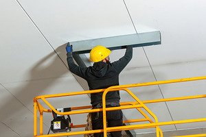 Worker installing metal profile for large plasterboard ceiling, an Industrial Photo by Antonio Gravante Market