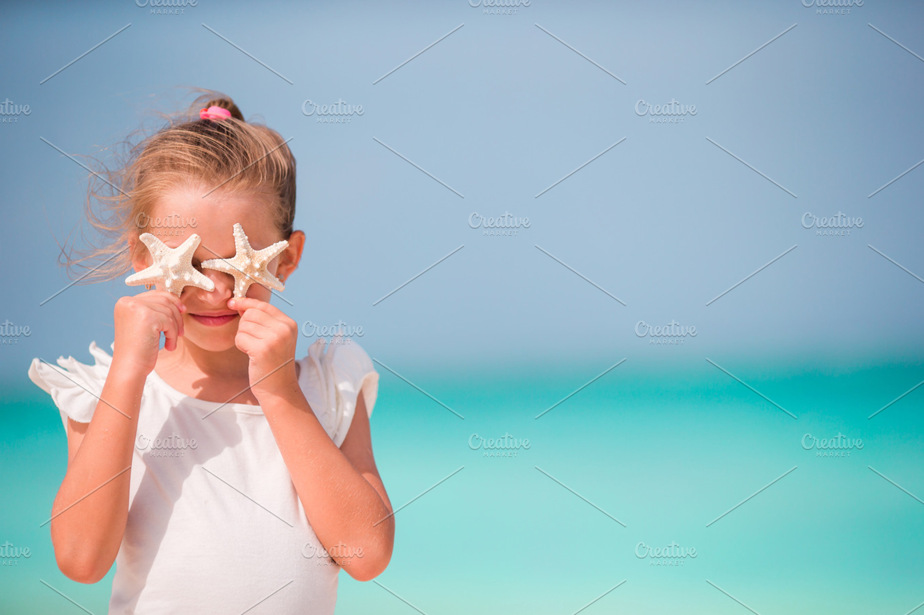 Adorable little girl with starfish on the beach featuring seastar, starfih, a Person Photo by travnikovstudio