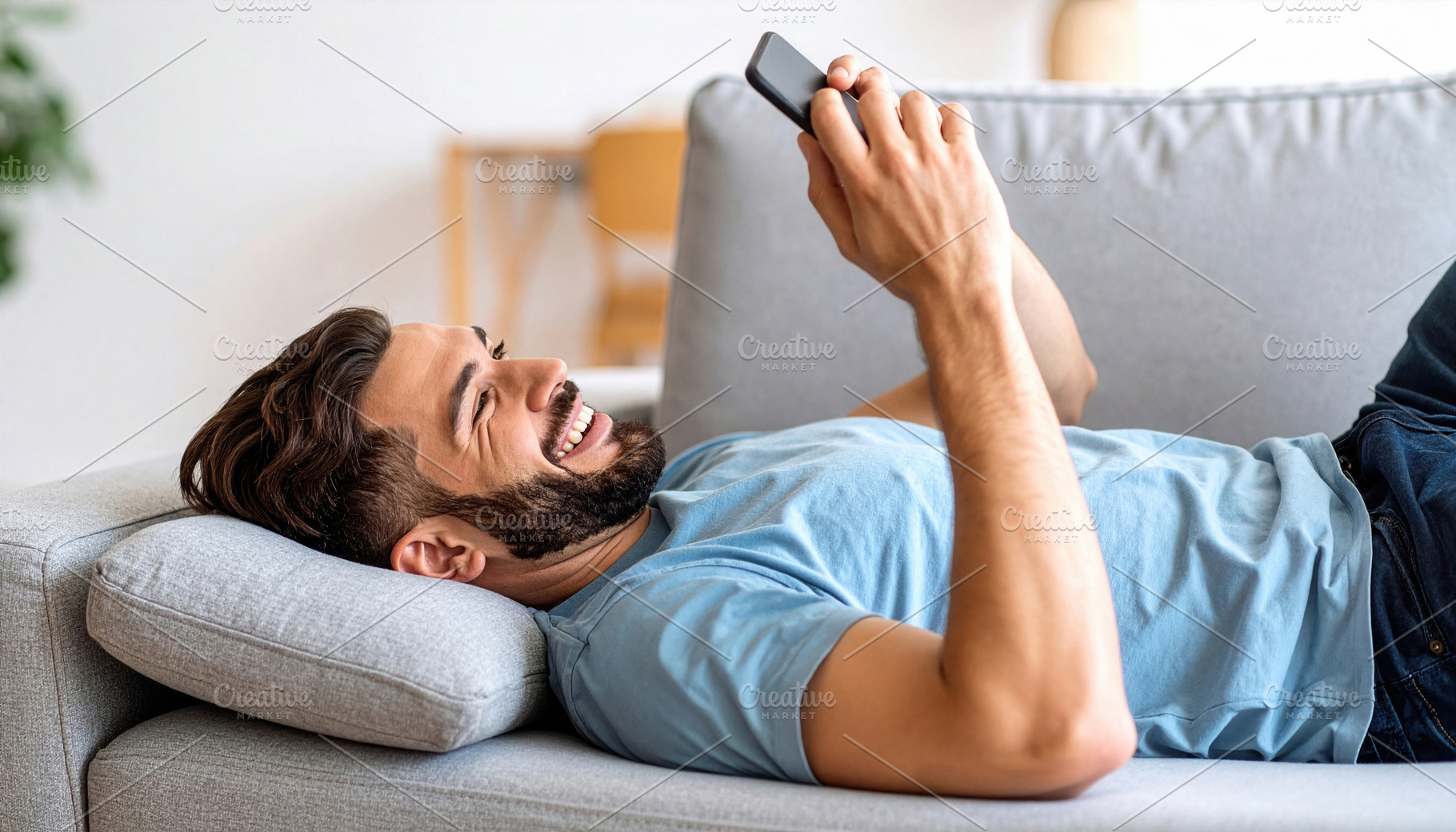 Smiling Man Relaxing with Smartphone on Sofa, a Photo by Davizro's Market