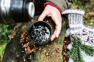 Hot cup of tea and thermos in forest