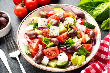 Greek salad in craft plate on black