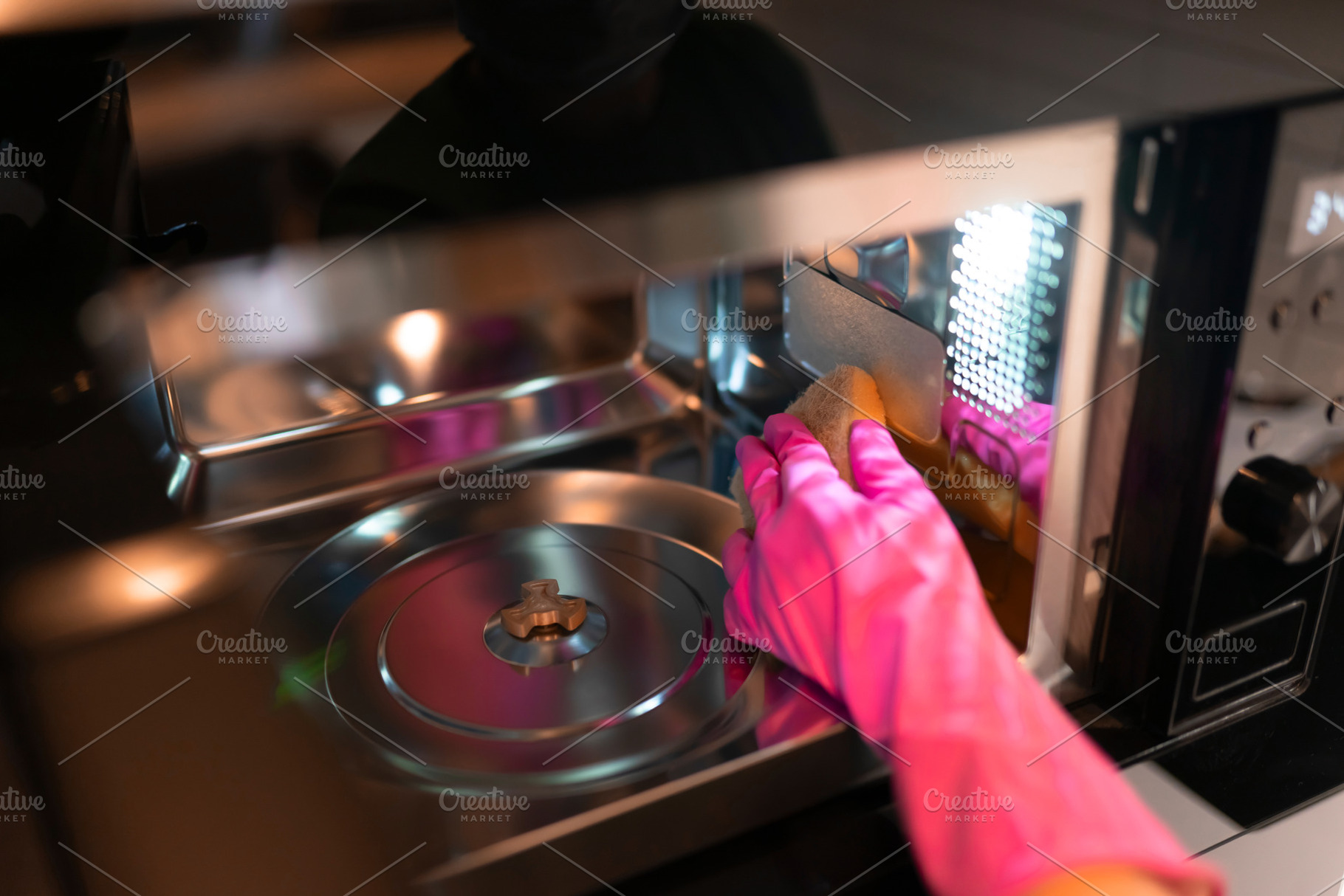 Hand in glove wipes the microwave, a Photo by Andrii Borodai