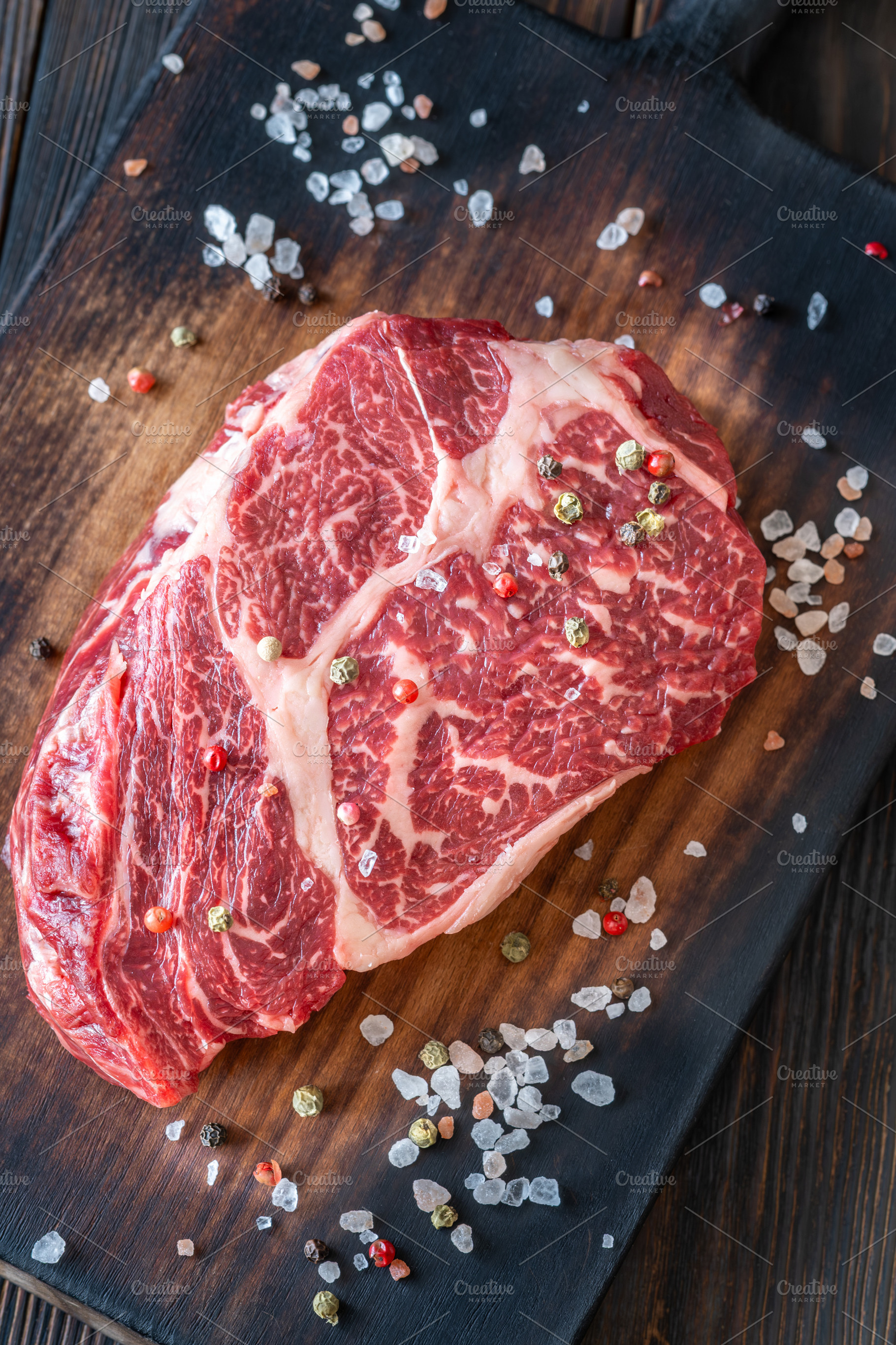 Raw ribeye steak on a wooden board w, a Food & Drink Photo by Alexander Prokopenko