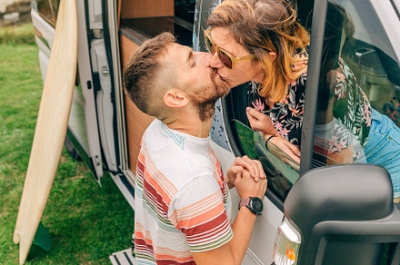 Couple kissing through the camper van window during a trip, a Holiday Photo by davidpereiras