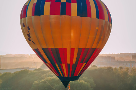Colorful hot air balloon takes off from green park in small european city at su