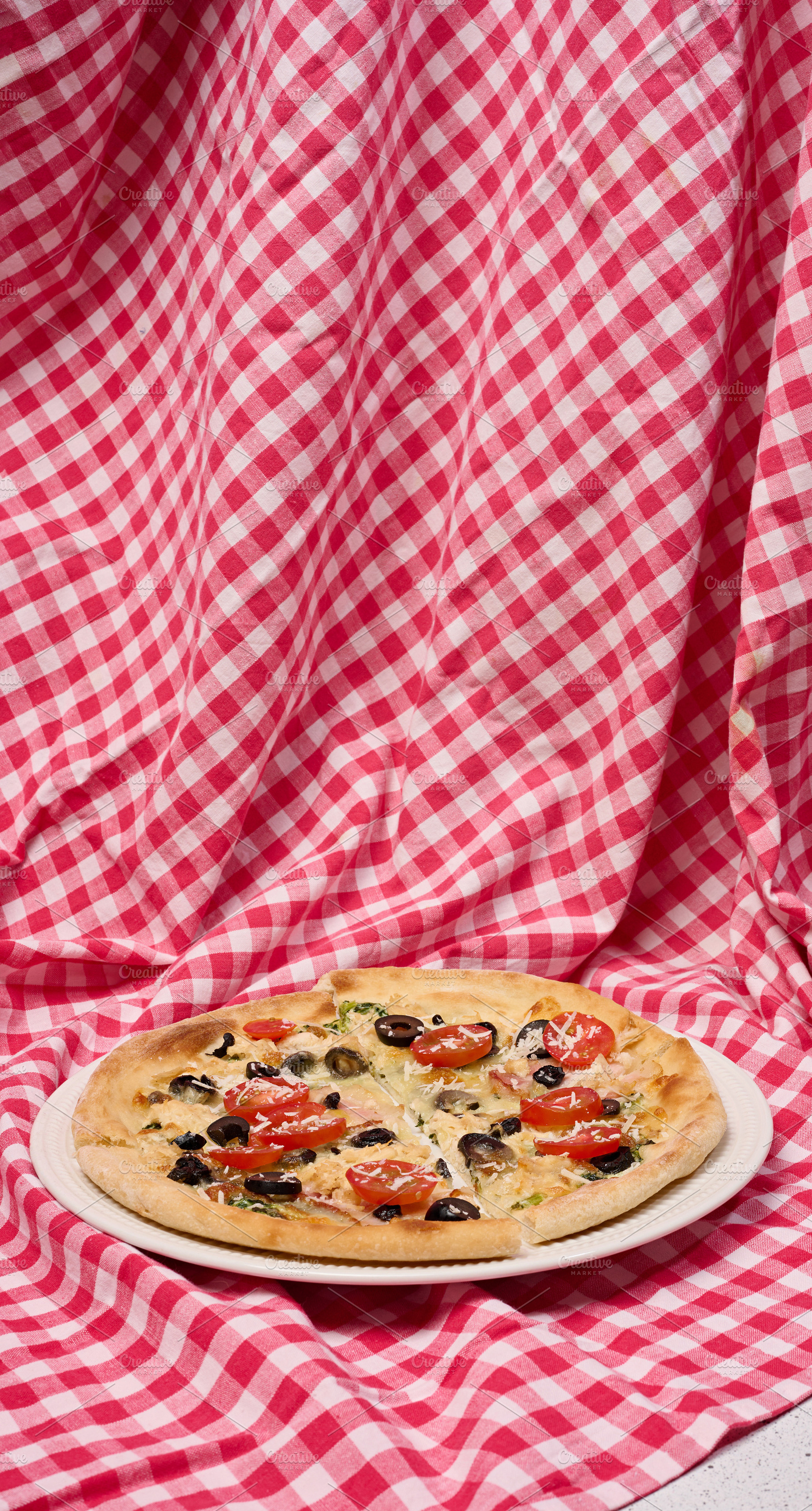 Pizza with cheese, tomatoes and olives on a white plate standing, a Food & Drink Photo by ndanko