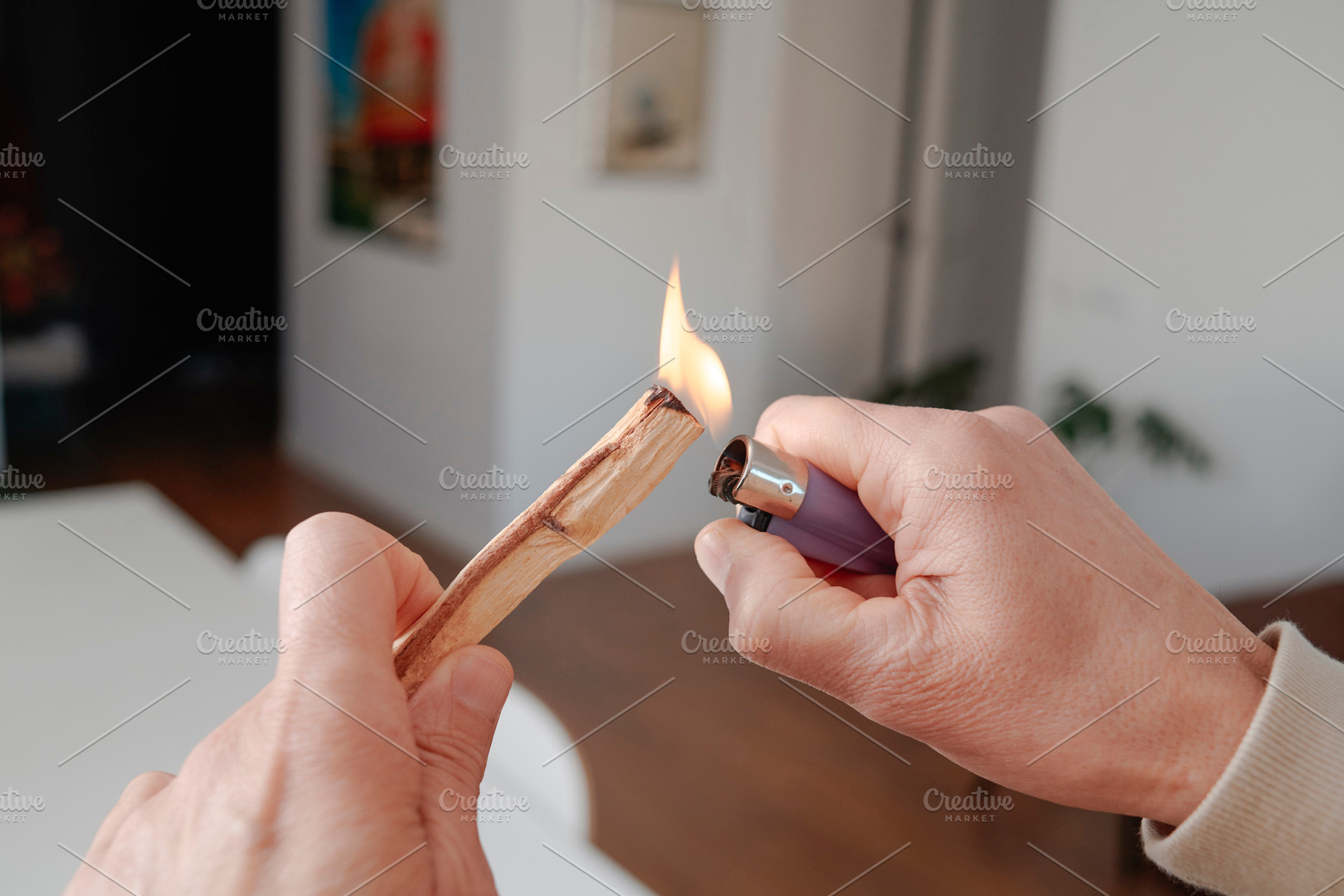 a man lights a sandalwood stick indoors, a Photo by Nito