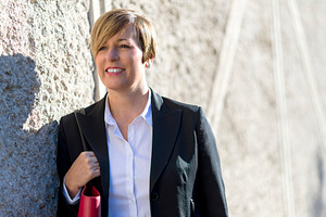 Smiling businesswoman leaning on stone wall, a Photo by RF Images