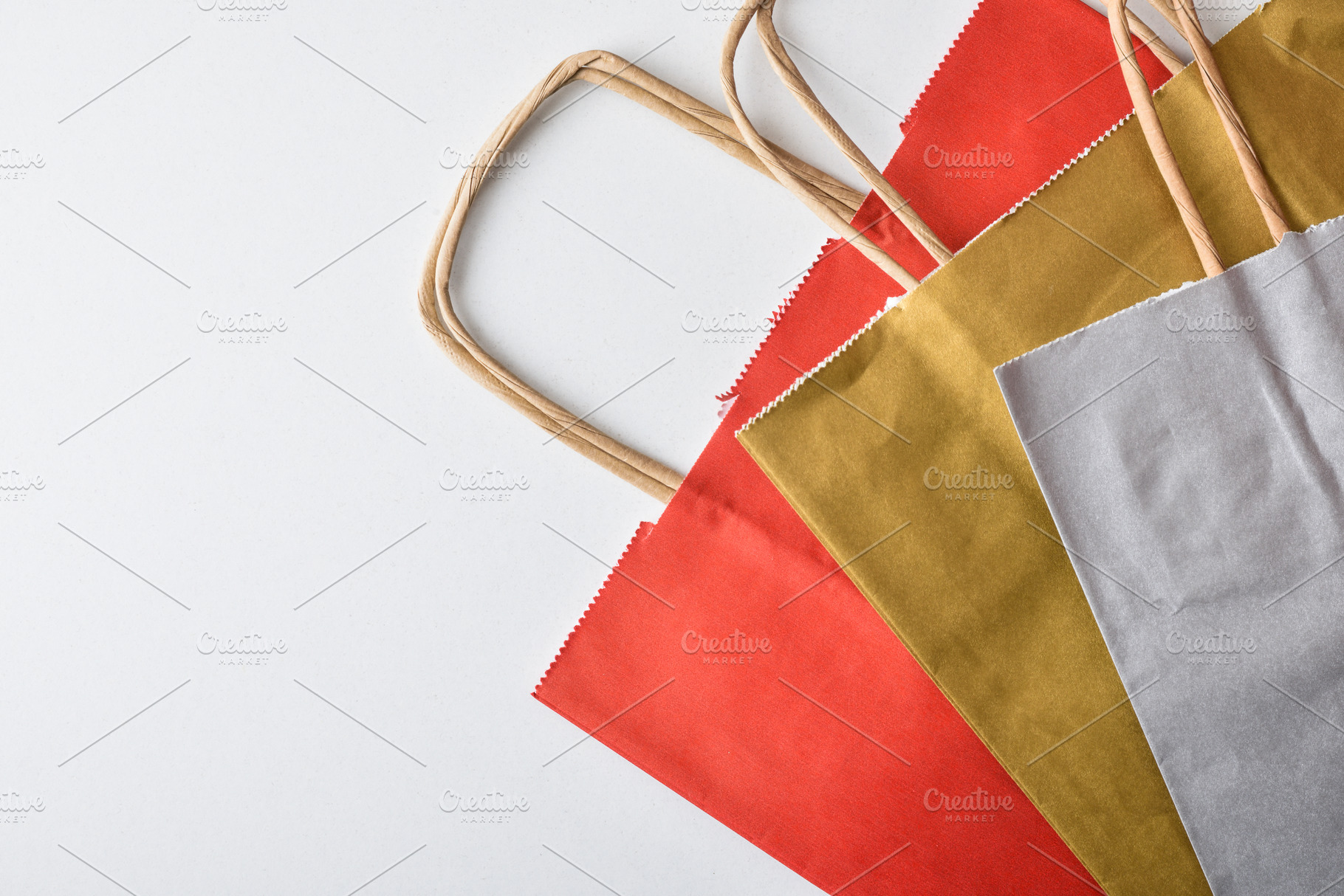 Empty, folded red, gold, and silver paper shopping bags, an Industrial Photo by Davizro's Market