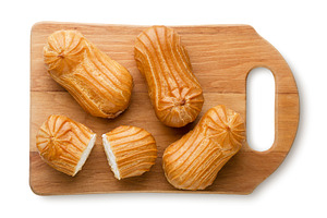Eclairs and halves on a wooden board, a Food & Drink Photo by innakreativ