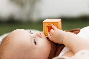Beautiful happy baby lying on blanket and playing with toys on b, a Person Photo by Sonjachni