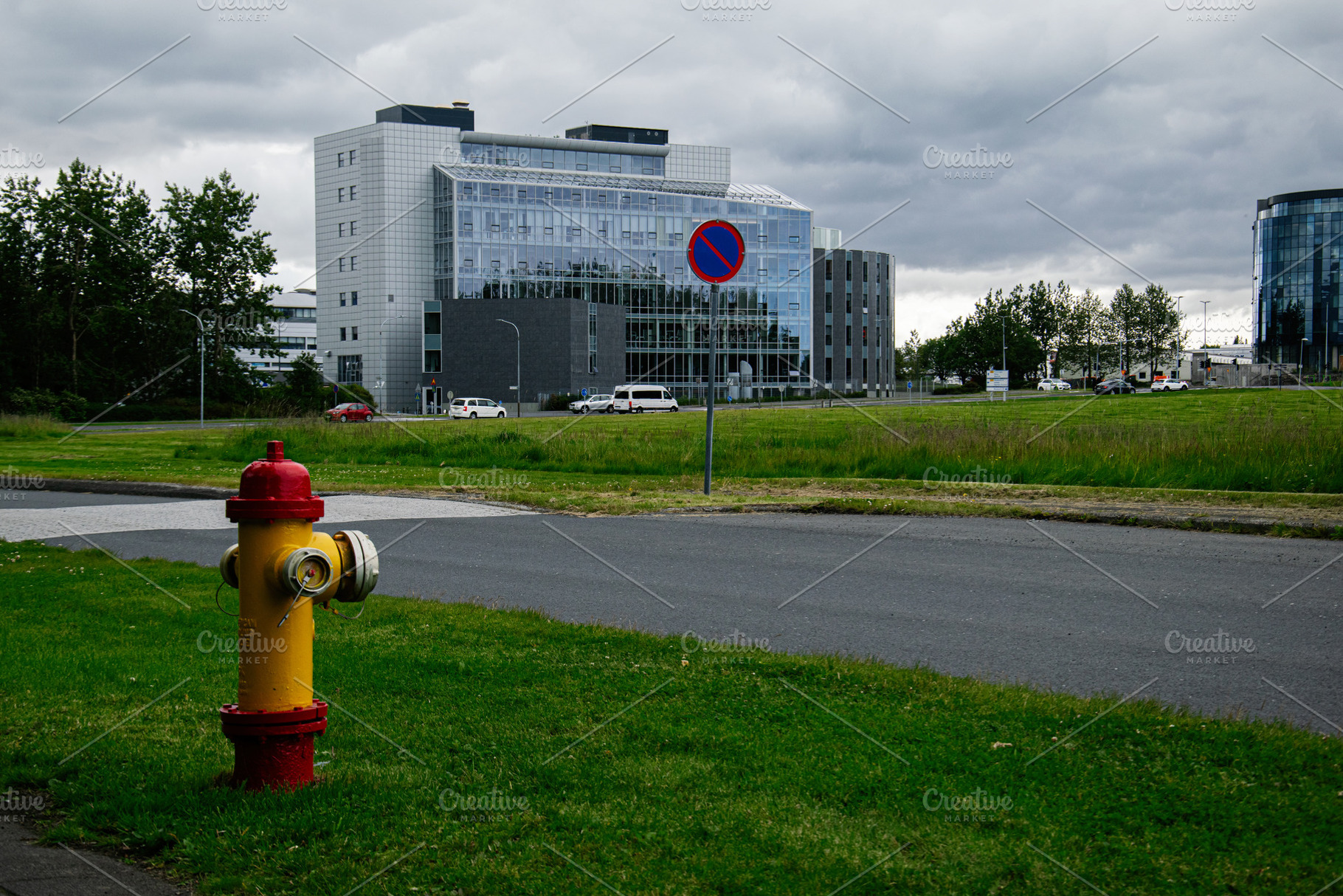 Urban scene in Reykjavik with a hydrant and modern building under cloudy skies, a Photo by AS photostudio
